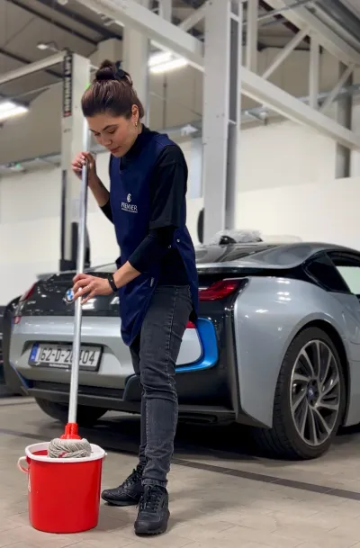 Premier cleaner mopping a car showroom floor beside a BMW