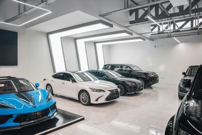 Cars on a gleaming white tiled floor in a bright car showroom