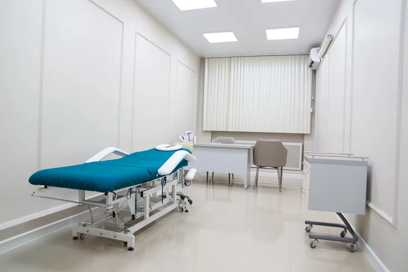 A clean, bright examination room with a treatment couch and desk