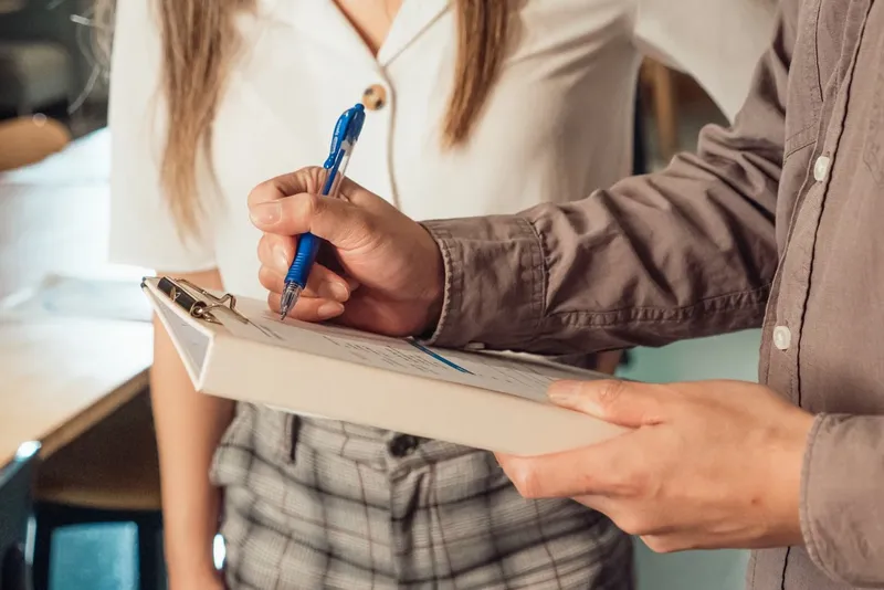 Two people filling in a checklist on a clipboard