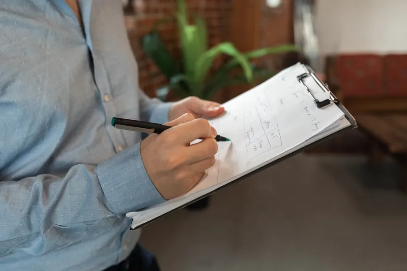 A person noting cleaning tasks on a clipboard during a site survey