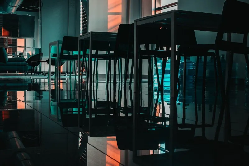 Dimly lit room with chairs and tables in shadow