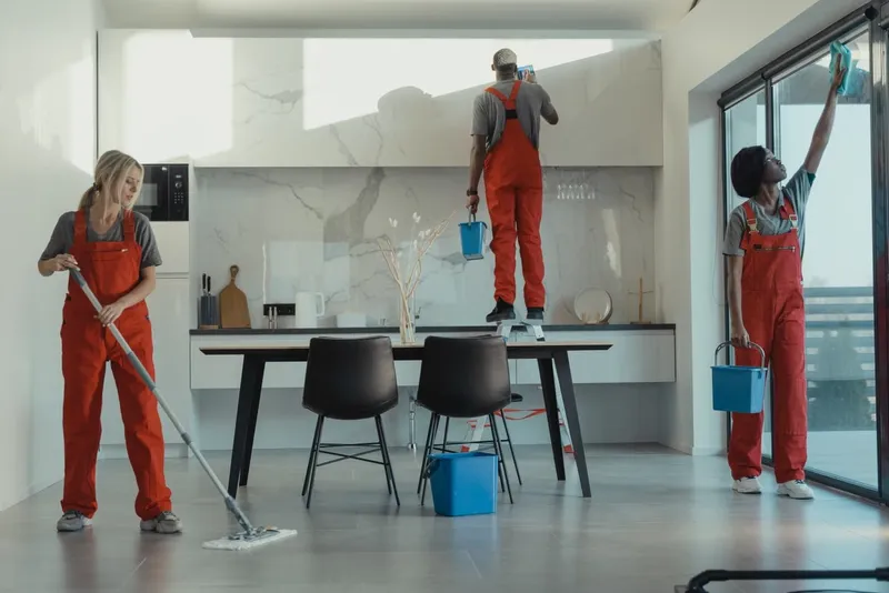Cleaners mopping the floor and wiping windows in a bright room
