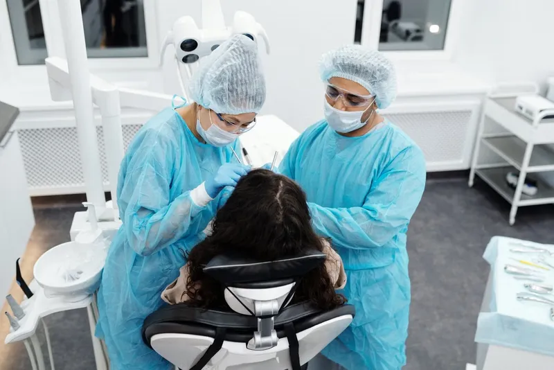 Dental team in protective gowns treating a patient in a clinic