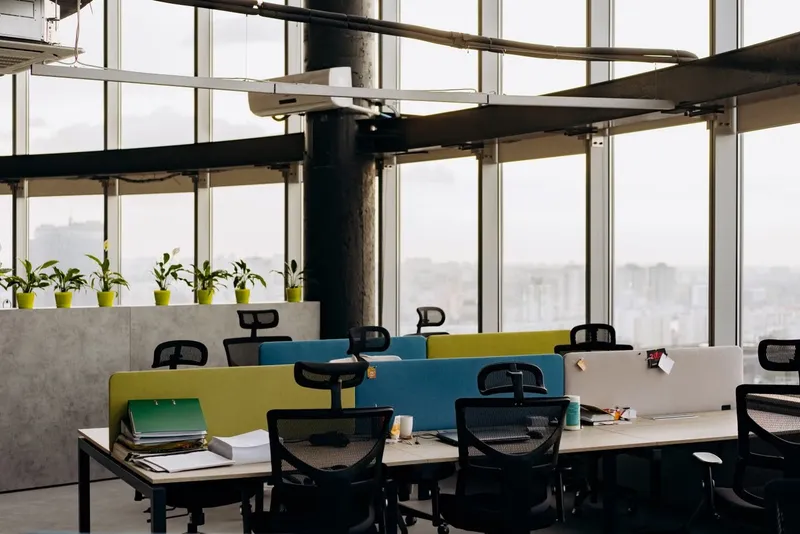 Open-plan office with colourful desk dividers and city views