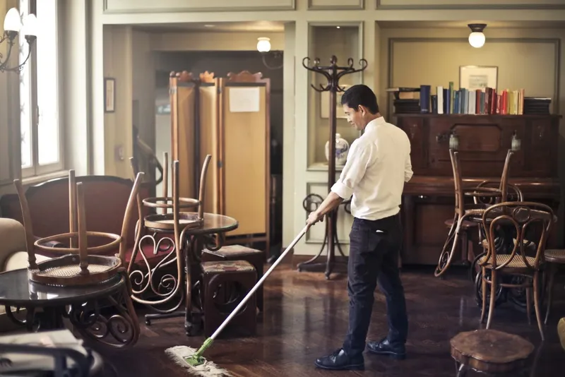 Man mopping a polished floor in a restaurant