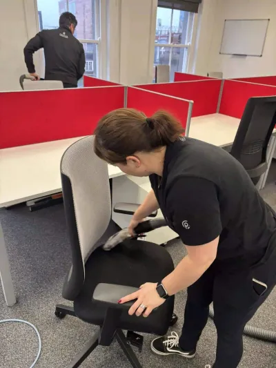 Premier cleaner vacuuming an office chair at a workstation