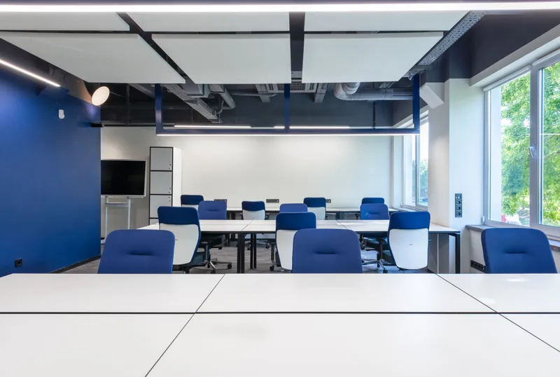 Rows of desks and blue chairs in a bright, empty open-plan office