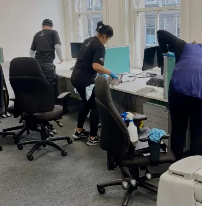 Premier cleaners wiping desks and chairs in an open-plan office
