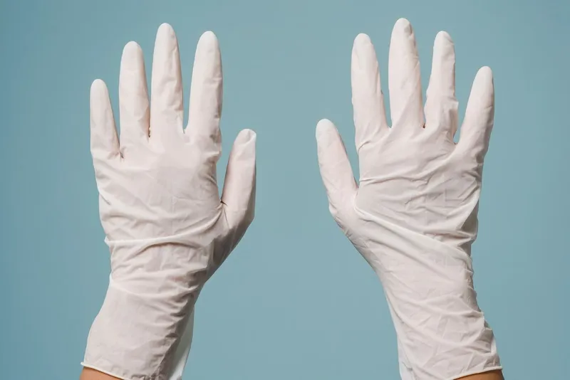 Hands in white disposable protective gloves