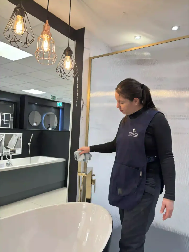 Premier cleaner wiping a basin unit in a bathroom showroom
