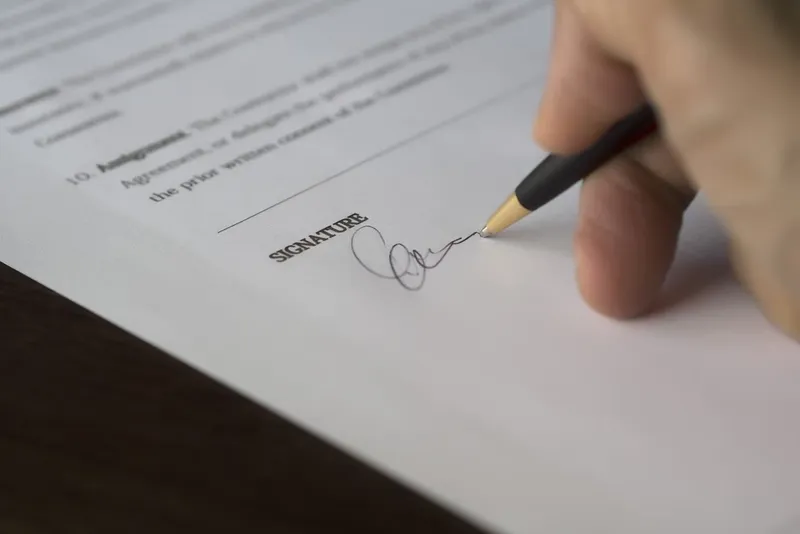 Hand signing a contract with a pen
