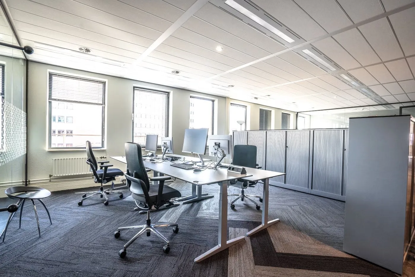 A tidy open-plan office with clear desks and clean carpet tiles