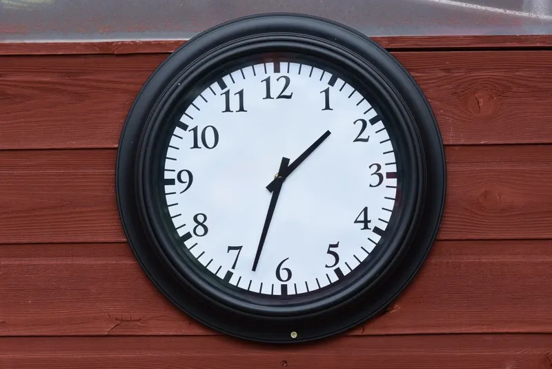 Black wall clock on a wooden wall