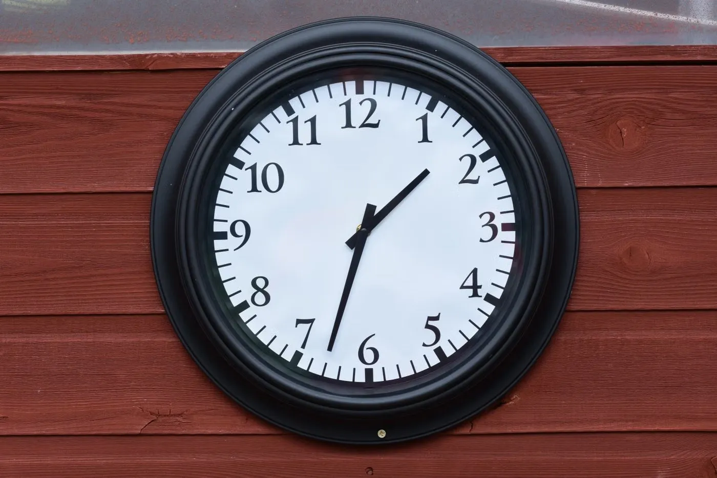 Black wall clock on a wooden wall