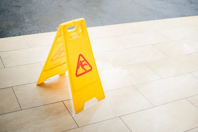 Yellow wet floor warning sign on a tiled floor