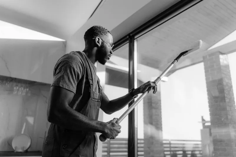 Cleaner washing large glass windows with an extension pole