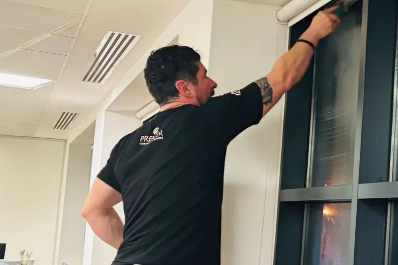 Premier cleaner wiping an office window frame