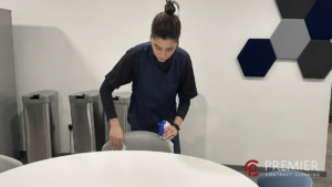 Commercial cleaner deep cleaning a shared office fridge in a Dublin workplace, sanitising shelves, door seals, drip tray, and hidden areas to eliminate persistent fridge odours