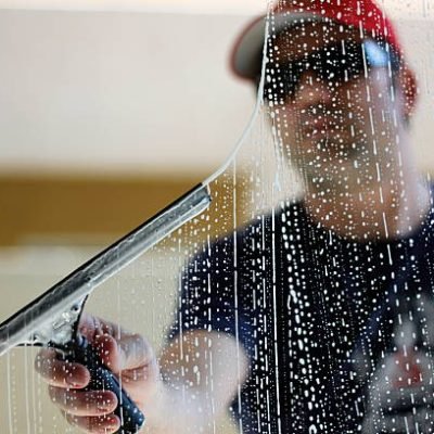 Worker using a squeegee to clean windows. Worker using a squeegee to clean windows.